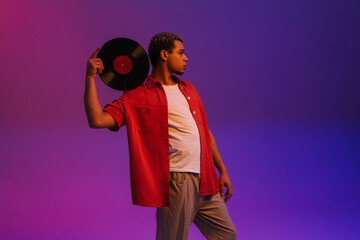 African guy posing with vinyl record isolated over purple neon background