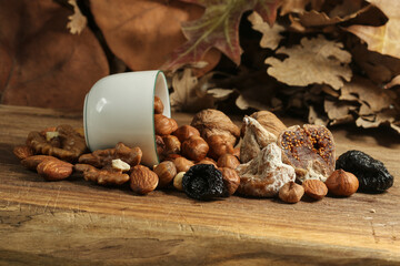 Different kinds of nuts and white cup, hazelnuts, almonds, walnut and dried fruits figs, plums. Vegetarian food.