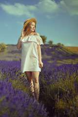 Beautiful girl on the lavender field. Beautiful woman in the lavender field on sunset. Soft focus. Provence, France. A girl in pink dress and hat walking trough lavender fields and enjoys nature.