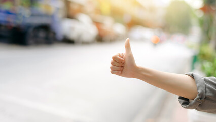 Smiling young Asian woman traveler hitchhiking on a road in the city. Life is a journey concept.