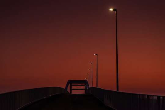 Fototapeta czerwony wschód słońca z mostem i drogą z latarniami