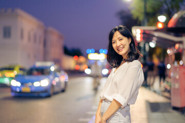 Portrait young beautiful asian woman smiling while travel by the Bangkok street twilight.