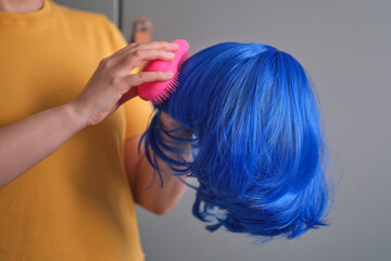 woman holds a bright wig in her hands. Womens beauty concept. unrecognizable woman combing her wig with a comb. how to check the quality of artificial hair