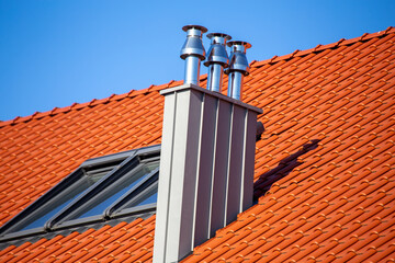 Schöner neuer Schornstein aus Edelstahl am Dach eines Wohnhauses