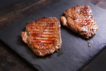 Grilled minute steak of marbled beef on a stone slate board, close up