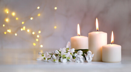 Fototapeta na wymiar Angels, snowdrops flowers and candles on table, blurred abstract background. Religious church holiday. symbol of faith in God, Christianity Feast. Romantic relaxation composition