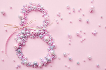 International Women's Day. Banner, flyer, beautiful postcard for March 8. Pearls in the shape of the number eight on a pink background.