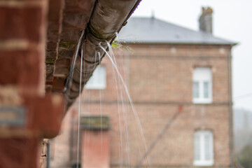 a gutter on a building, an old drainpipe close-up, water flows through rotten metal, there is a...