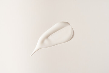 A smear of cosmetic cream. A white creamy drop of skin care cream. Fresh, smooth brushstroke on a light grey background with space to copy. High quality photo