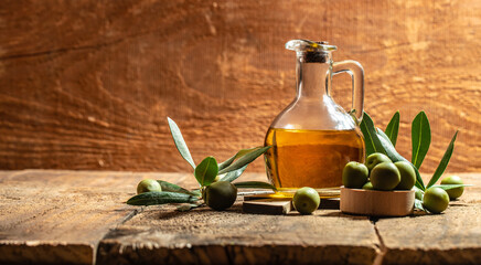 Glass container with olive oil branches and olives on a wooden background. Long banner format