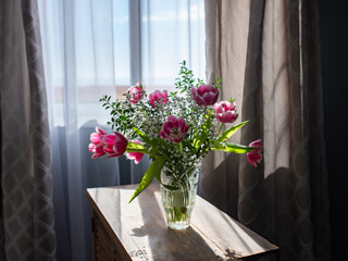 Beautiful bouquet of tulips in glass vase on white marble table. Space for text