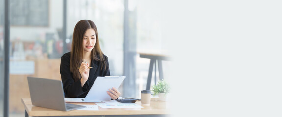 Attractive asia busy business woman consultant auditor working at modern office with balance sheet...