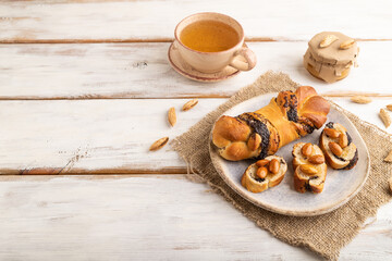 Homemade sweet bun with honey almonds and cup of green tea on a white. side view, copy space.