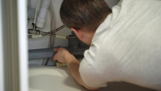 Plumber repairs plumbing pipes sewerage in kitchen sink. Removing blockage clog in drain pipe. Replacement of plumbing pipes