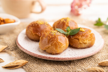 Traditional turkish dessert sekerpare with almonds and honey on white wooden, side view, selective focus.