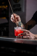 The bartender prepares a red cocktail.