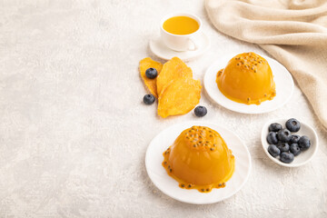 Mango and passion fruit jelly with blueberry on gray concrete, side view, copy space.