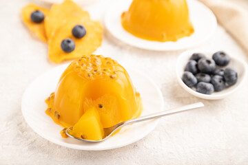 Mango and passion fruit jelly with blueberry on gray concrete, side view, selective focus.