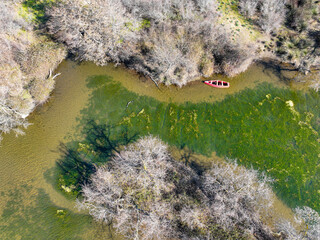 Aerial drone view of red small boat on Longoz forest lake in winter season. Karacabey Longoz Forests. Karacabey, Bursa,Turkey