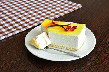 healthy citrus cheesecake decorated with chocolate and pomegranate seeds on saucer with teaspoon