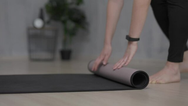 close up of woman preparing a yoga mat for training on the floor at home 
