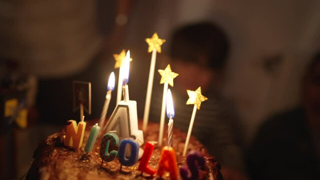 Birthday cake anniversary celebration with candles close up with the name nicolas written on top. 4 years old number