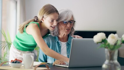 Video of happy grandmother using laptop with her granddaughter at home. - Powered by Adobe