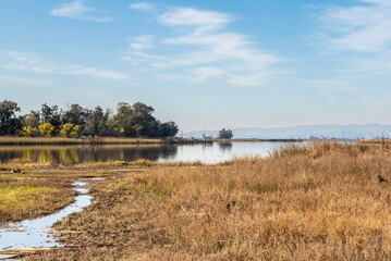 Grizzly Slough, a canal in the  Suisun Marsh near Grizzly Island road on a partly cloudy day with blue sky copy-space. This is part of the largest blackish water marsh on the West Coast USA