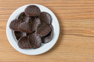 Dark chocolate chips on a plate on a pine table
