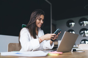 Happy woman using smartphone at table