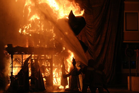 Bomberos protegiendo un edificio para que no se queme con la falla ardiendo, las figuras en llamas en el d&iacute;a de la crem&aacute; en Valencia