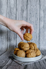 Mão segurando noz natural com casca em fundo rústico de madeira