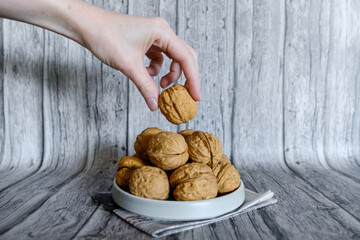 Mão segurando noz natural com casca em fundo rústico de madeira