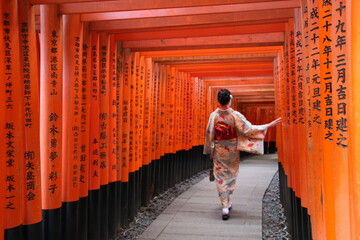 Japonesa entrando en el santuario de Fushimi Inari en Kyoto entre toris naranjas