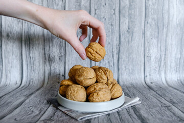 Mão segurando noz natural com casca em fundo rústico de madeira