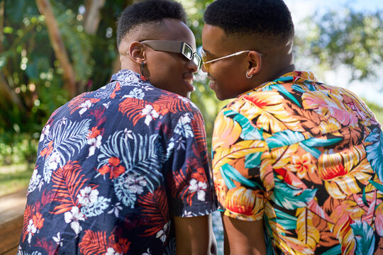 Affectionate gay male couple in Hawaiian shirts kissing