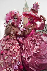 Fototapeta na wymiar Couple of people dressed up for the Venice Carnival wearing pink sweets