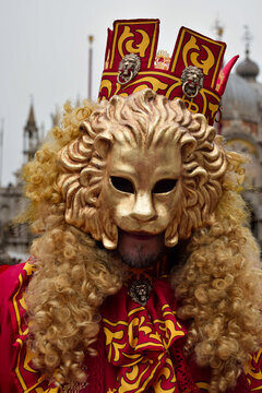 Person dressed up for Carnival of Venice wearing golden lion emblem mask