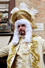 Person dressed up for Carnival of Venice wearing golden clothes