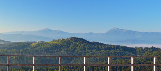 Panoramic view from the terrace on the Carpathian mountain range. Hoverla and Petros mountain peaks in the background.