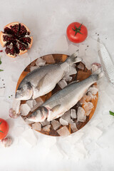 frozen fresh dorado on a wooden board on the ice on a gray rock background