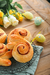 Easter breakfast Holliday concept. Easter bunny buns rolls with cinnamon made from yeast dough with orange glaze, easter decorations, colored eggs on old wooden background. Easter Holliday card.