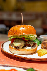 Organic vegetarian burger with plant based falafel balls, vegan cheese, green lettuce and baked potatoes