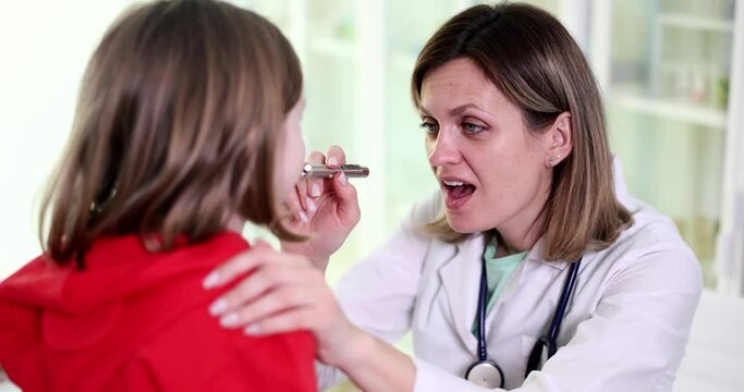 ENT doctor examines throat and mouth of little girl