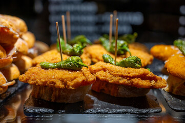 Typical snack of Basque Country, pinchos or pinxtos skewers with small pieces of bread, sea food, eggs, cheese, jamon served in bar in San-Sebastian or Bilbao, Spain