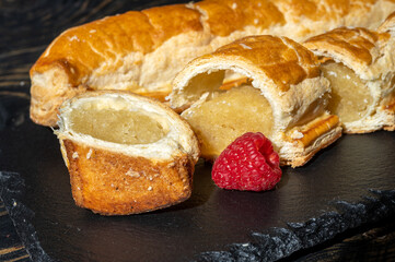 Fresh baked Dutch filled spicy cookies from puff pastry with almonds in autumn colors on dark stone