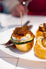 White board with typical snack of Basque Country, pinchos or pinxtos skewers with small pieces of bread, courgette, sea food, eggs, cheese, served in bar in San-Sebastian or Bilbao