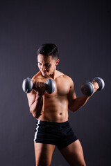 Portrait young fitness sporty strong man bare-chested muscular sportsman isolated on grey dark.