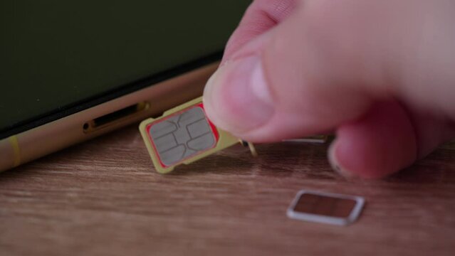 Person inserting a sim card into back of mobile phone, Sim card in tray being inserted into phone
