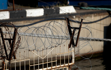 Restricted area. Passage is prohibited closed. Border from old barbed metal barrier wire. Concept of border, prison, war, military base, refugees. Selective focus. As a conceptual modern background